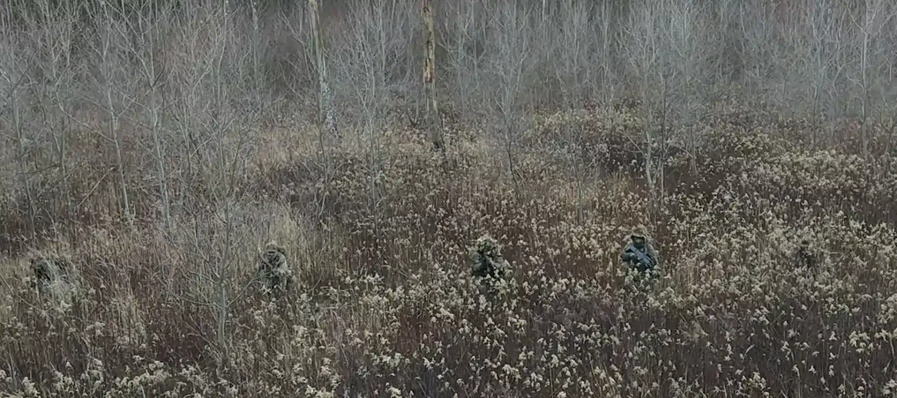Grupa strzelcow z maskowaniem maszeruje w polu, szkolenie sere