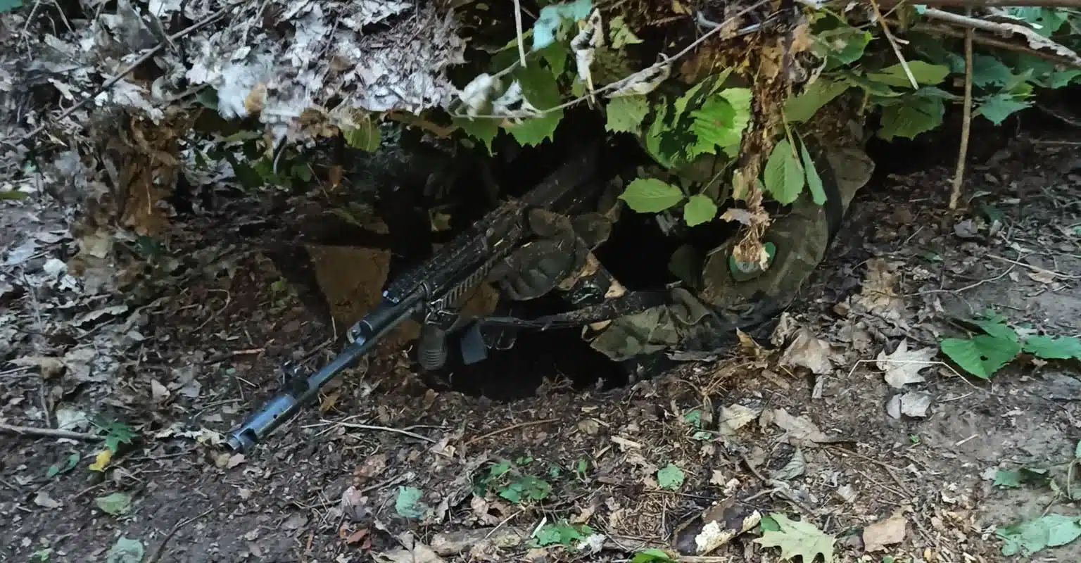Strzelec skryty w lesie na szkoleniu SERE