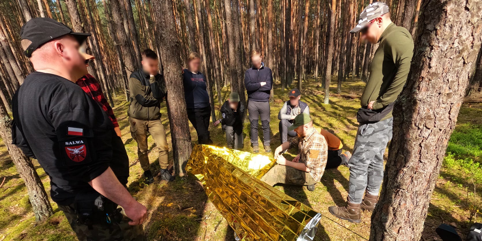 Obóz survivalowy dla dorosłych - instruktor pokazuje schronienie survivalowe.